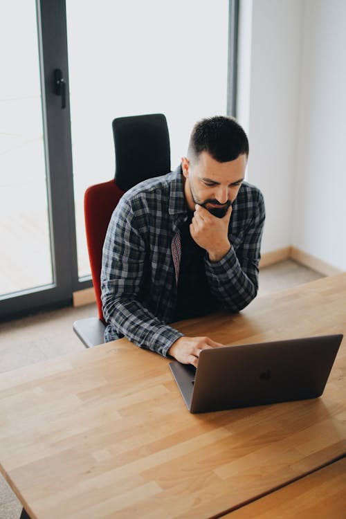 a man using his laptop on a wooden desk