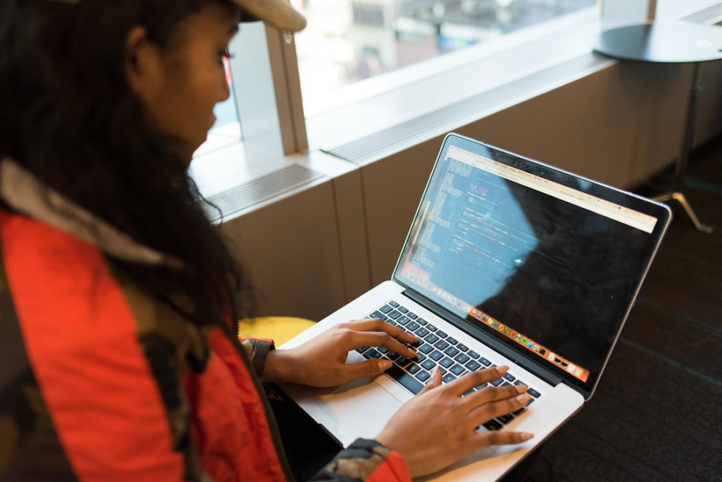 a woman in an orange jacket using her laptop